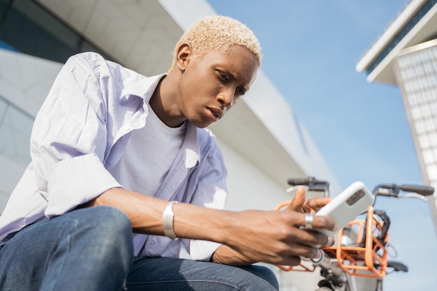 Foto homem afro-americano com cabelo estiloso usando aplicativo móvel fazendo compras on-line na rua