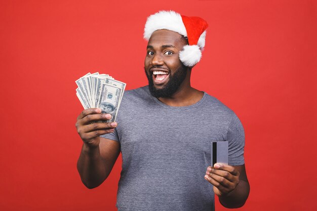 Homem afro-americano com chapéu de Papai Noel segurando dinheiro e cartão de crédito