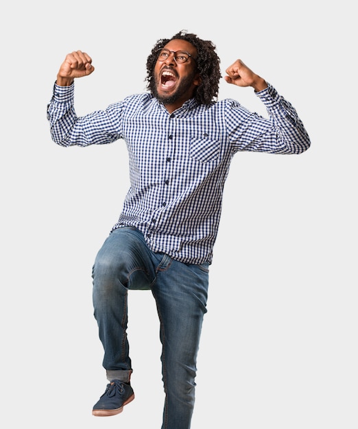 Homem afro-americano de negócios bonito muito feliz e animado, levantando os braços, comemorando uma vitória ou sucesso, ganhando na loteria