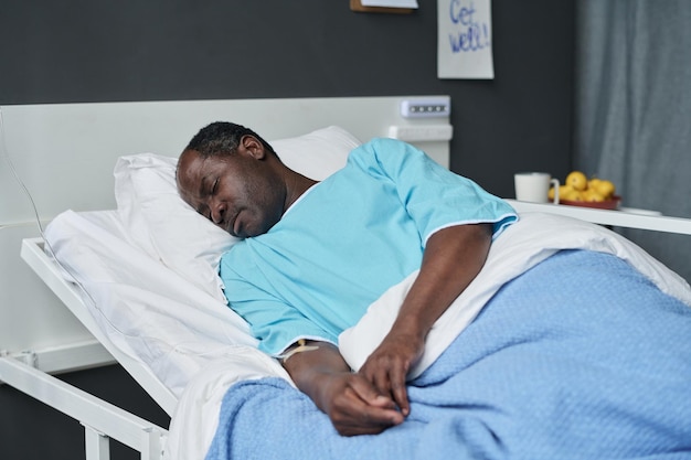 Homem afro-americano descansando na cama na enfermaria durante sua reabilitação no hospital