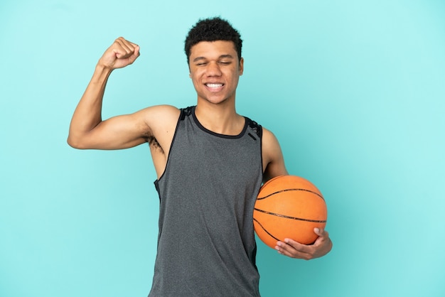 Homem afro-americano do jogador de basquete isolado em um fundo azul fazendo um gesto forte