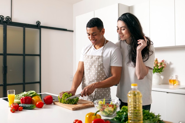 Foto homem afro-americano e mulher europeia preparando salada de legumes e verduras juntos