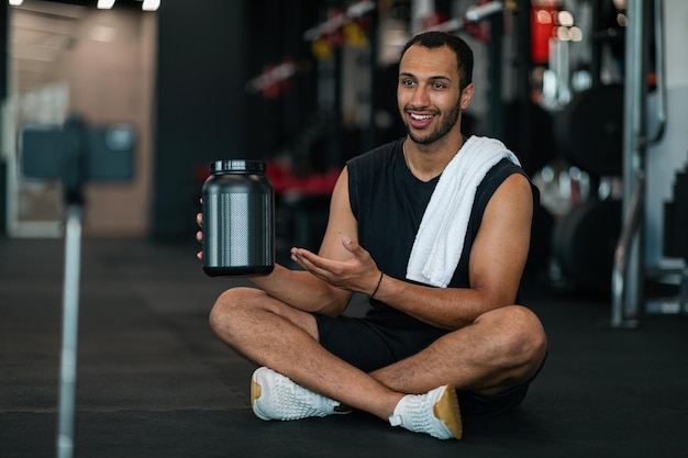 Homem afro-americano esportivo gravando conteúdo de vídeo enquanto está sentado na academia