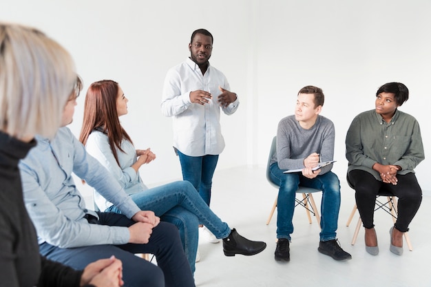 Homem afro-americano falando com pacientes de reabilitação