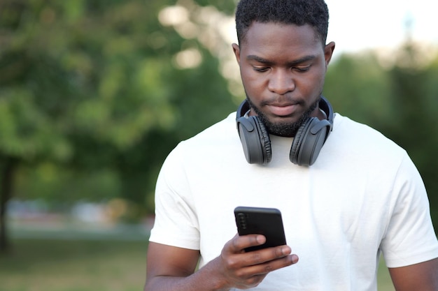 Homem afro-americano fica digitando mensagens no smartphone preto