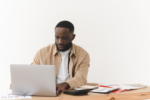 Homem afro-americano focado trabalhando em laptop em casa programador freelancer negro trabalha na mesa