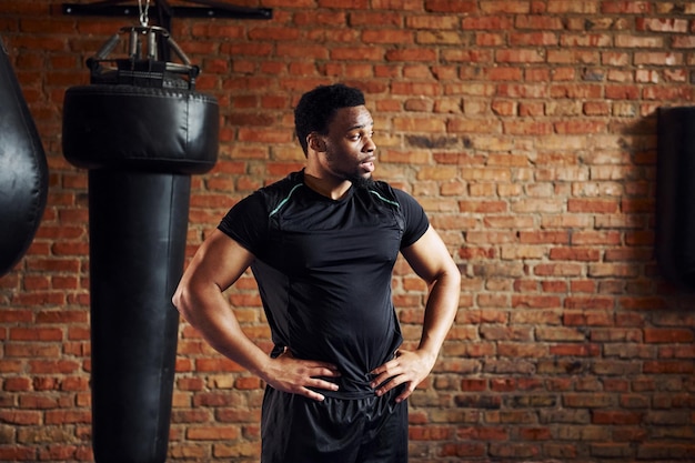 Homem afro-americano forte em roupas esportivas em pé no ginásio