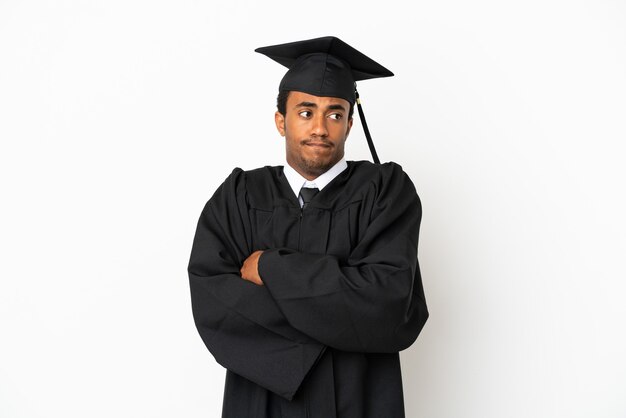 Homem afro-americano graduado em universidade sobre fundo branco isolado, fazendo gestos de dúvida enquanto levanta os ombros