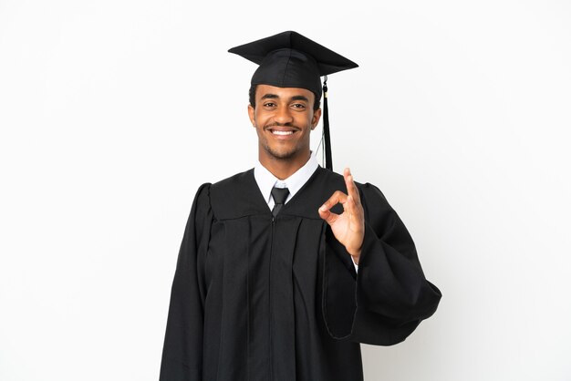 Homem afro-americano graduado em universidade sobre fundo branco isolado, mostrando sinal de ok com os dedos