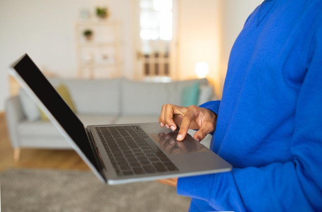 Homem afro-americano irreconhecível usando laptop em casa recortado