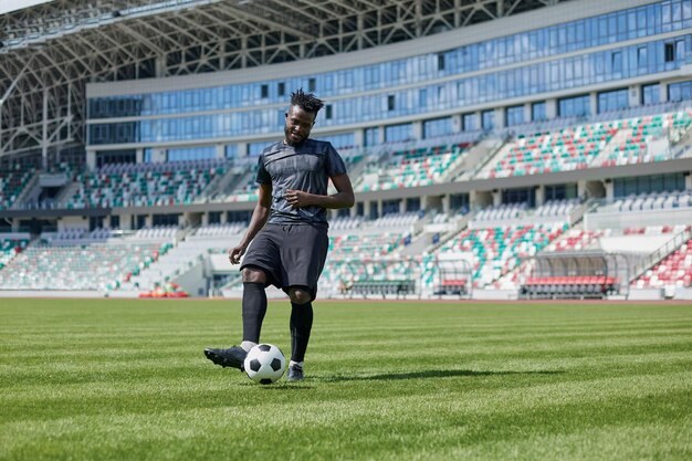 Homem afro-americano jogando futebol no campo do estádio