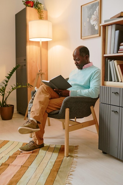 Homem afro-americano lendo um livro em uma cadeira