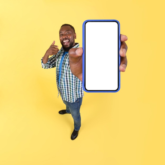 Homem afro-americano mostrando fundo amarelo de tela em branco grande smartphone