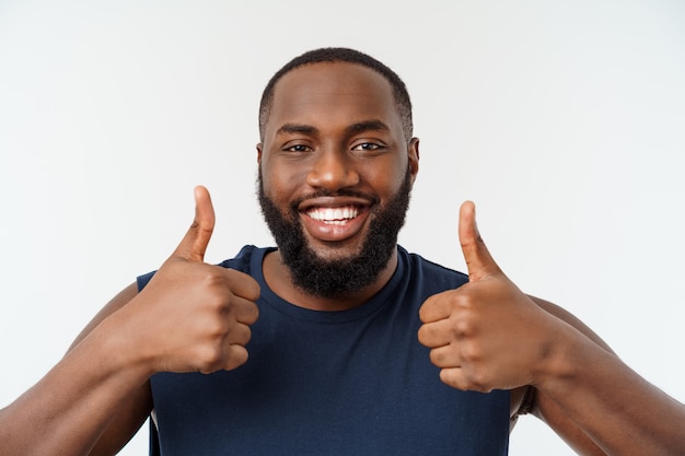 Homem afro-americano novo sobre o desgaste vestindo isolado do esporte que sorri com a cara feliz que olha com polegar acima.