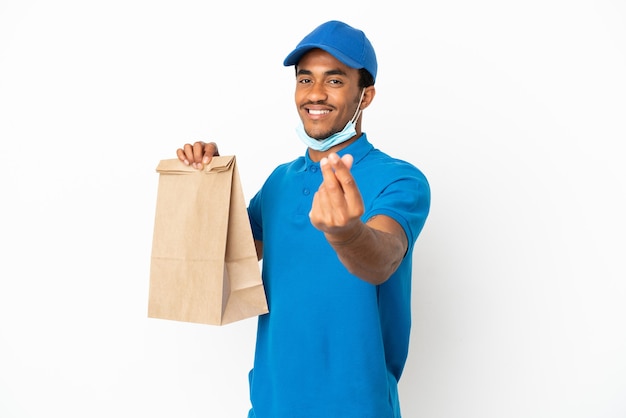 Homem afro-americano pegando uma sacola de comida para viagem isolada no fundo branco fazendo gesto de dinheiro