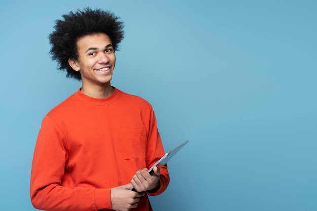 Homem afro-americano segurando tablet digital isolado em fundo azul, copie o espaço