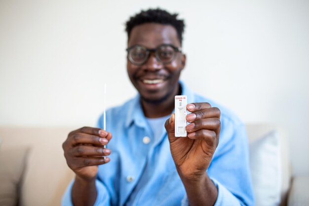 Homem afro-americano segurando um dispositivo de teste negativo Jovem feliz mostrando seu teste rápido de Coronavirus Covid19 negativo Coronavirus