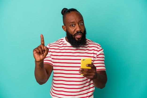 Homem afro-americano segurando um telefone celular isolado em um fundo azul