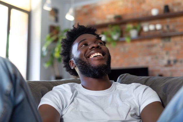 Homem afro-americano sorridente relaxando em casa e vendo televisão no sofá com espaço para copiar