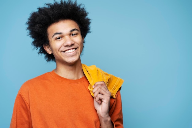 Homem afro-americano sorridente vestindo roupas elegantes isoladas em fundo azul, copie o espaço