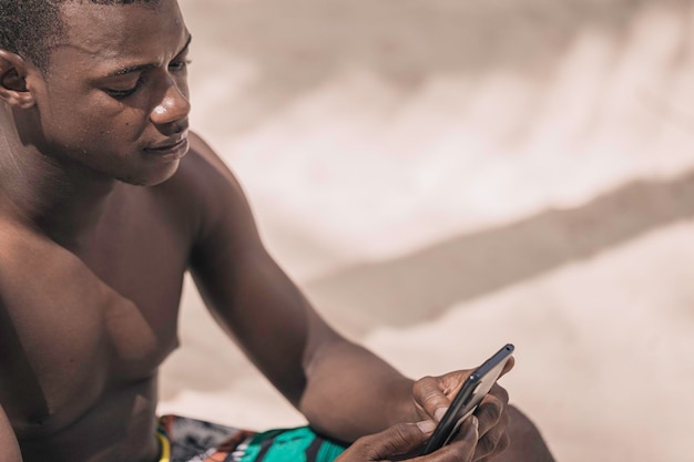 Homem afro-americano usando smartphone na praia