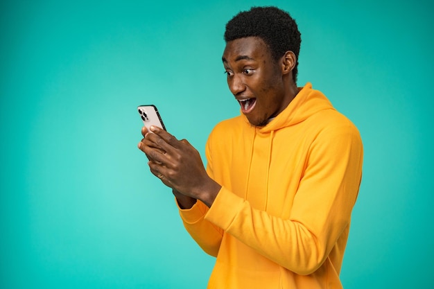 Homem afro-americano usando smartphone sobre fundo de hortelã isolado