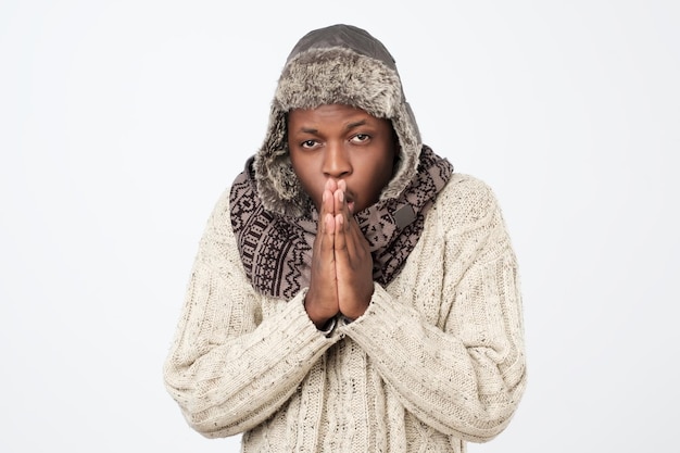 Homem afro-americano vestindo roupas de inverno, mas sentindo frio em um fundo branco