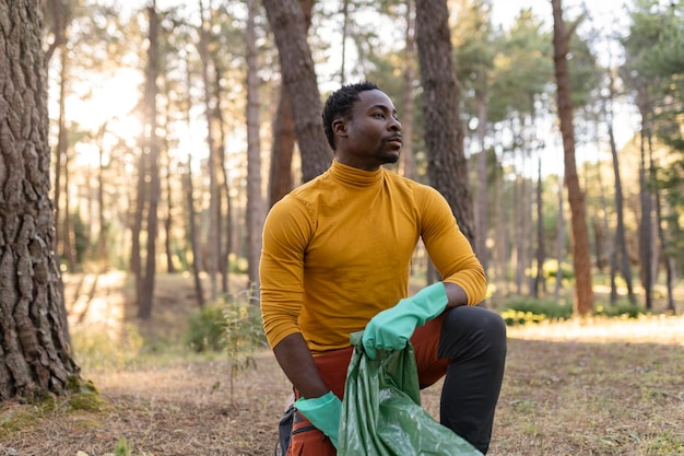 homem afro-americano voluntário recolher lixo na floresta conceito de ecologismo cuidado com o meio ambiente