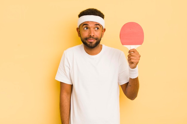 Homem afro negro encolhendo os ombros sentindo-se confuso e incerto conceito de pingue-pongue