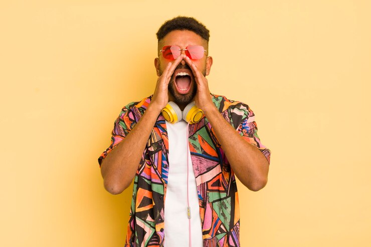 Foto homem afro negro se sentindo feliz dando um grande grito com as mãos ao lado do conceito de óculos de sol e fones de ouvido