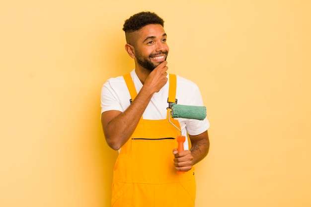 Homem afro negro sorrindo com uma expressão feliz e confiante com a mão no queixo pintando o conceito de casa