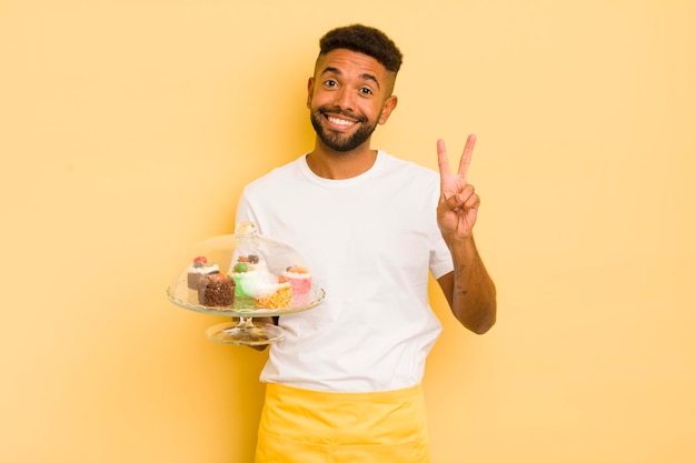 Homem afro negro sorrindo e olhando feliz gesticulando vitória ou paz conceito de bolos caseiros