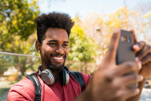 Homem afro tirando selfies com telefone.