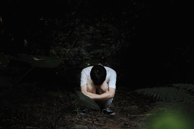 Homem agachado na floresta