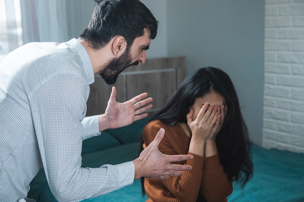 Homem agressivo batendo em mulher na sala