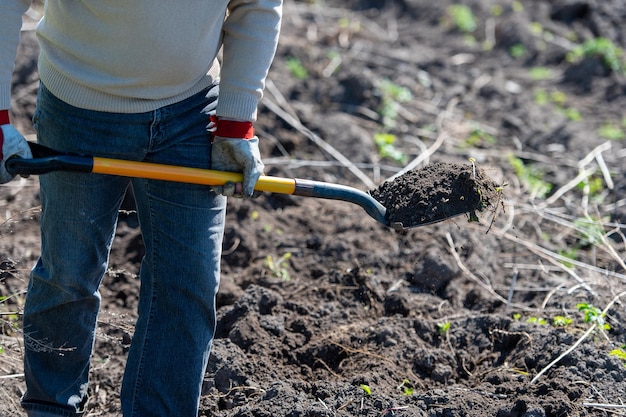 Homem agricultor trabalhando com ferramentas de jardim pá e carrinho de mão no local de uma casa de campo