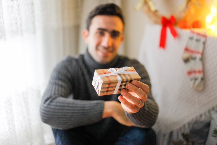 Foto homem aguentar uma caixa de presente com fita branca com decorações de natal