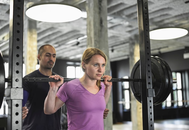 Foto homem ajudando mulher a se exercitar no ginásio