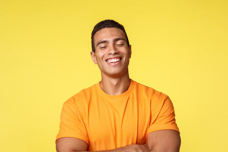 Foto homem alegre bonito em camiseta, rindo com os olhos fechados