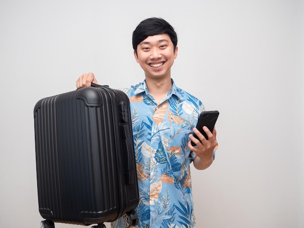 Homem alegre camisa de praia sorriso feliz segurando bagagem e smartphone