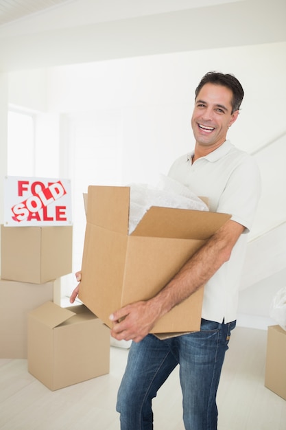 Homem alegre carregando caixas em uma nova casa