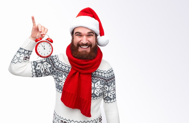 homem alegre com chapéu de natal segurando um relógio e sorrindo