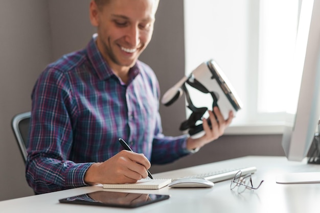 Homem alegre com óculos VR escrevendo no caderno