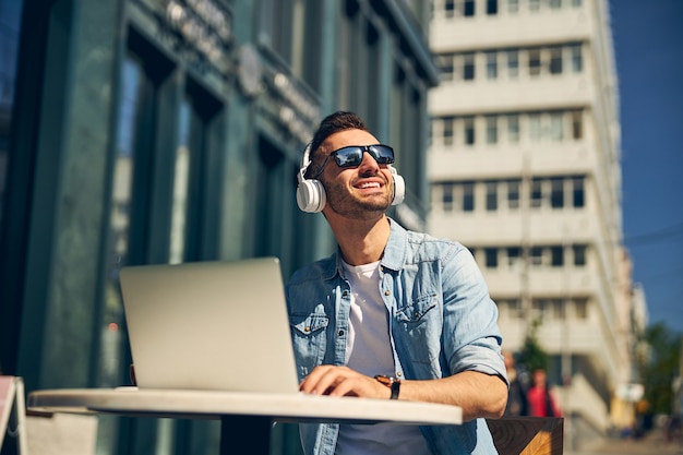 Homem alegre com um sorriso no rosto enquanto olha para o céu ensolarado