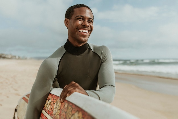 Homem alegre com uma prancha de surf na praia