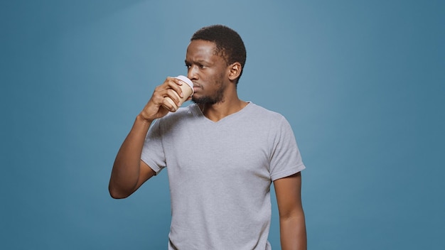 Homem alegre, desfrutando de uma xícara de café para se refrescar pela manhã, posando na frente da câmera. Pessoa feliz se sentindo cansada e bebendo cafeína na caneca, fazendo uma pausa com uma bebida deliciosa.