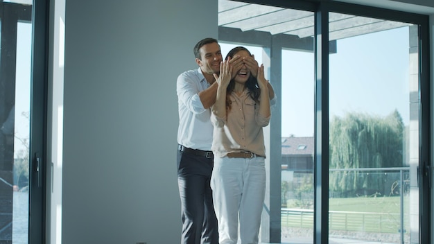 Homem alegre fechando olhos mulher em casa nova Esposa feliz desfrutando de casa de luxo