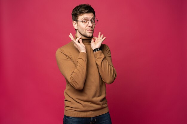 Homem alegre, rindo e olhando para a câmera. Retrato de um jovem feliz em pé sobre fundo rosa.