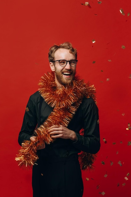 Homem alegre ruivo de óculos e jibóia dourada na festa de ano novo com foto de estúdio de confete