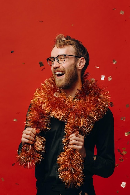 Homem alegre ruivo de óculos e jibóia dourada na festa de ano novo com foto de estúdio de confete